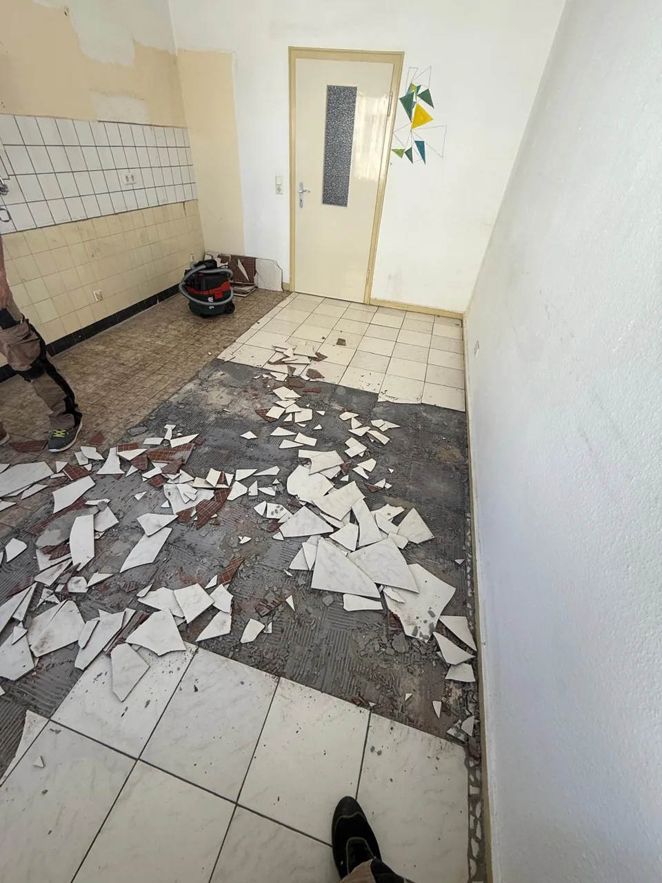 Teilweise entfernter Fliesenboden mit Bruchstücken