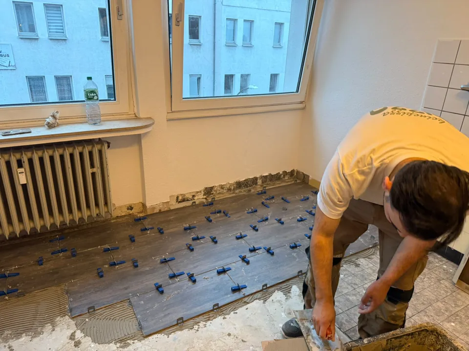 Verlegung von Bodenfliesen mit Verlegehilfen am Fenster